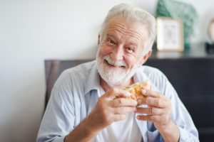 Man with dental implants eating burger